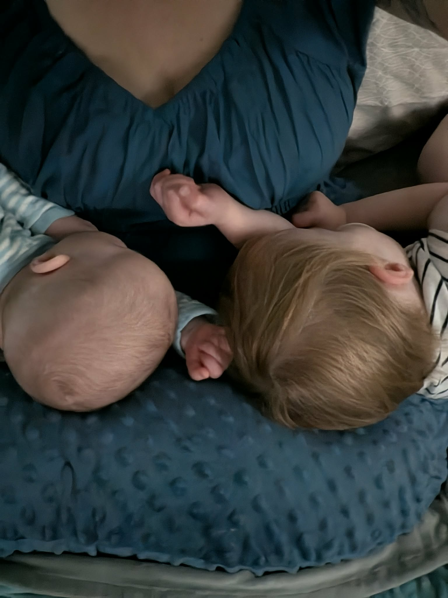 The new baby and his toddler brother lying side by side on a nursing pillow