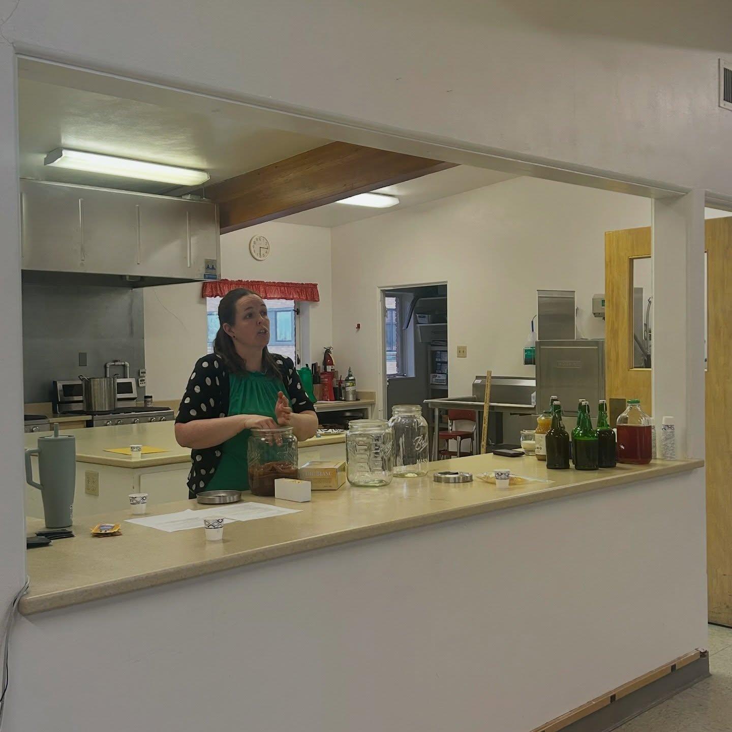 Teaching a kombucha class at the local extension office kitchen, with brewing jars and bottles lined up on the counter